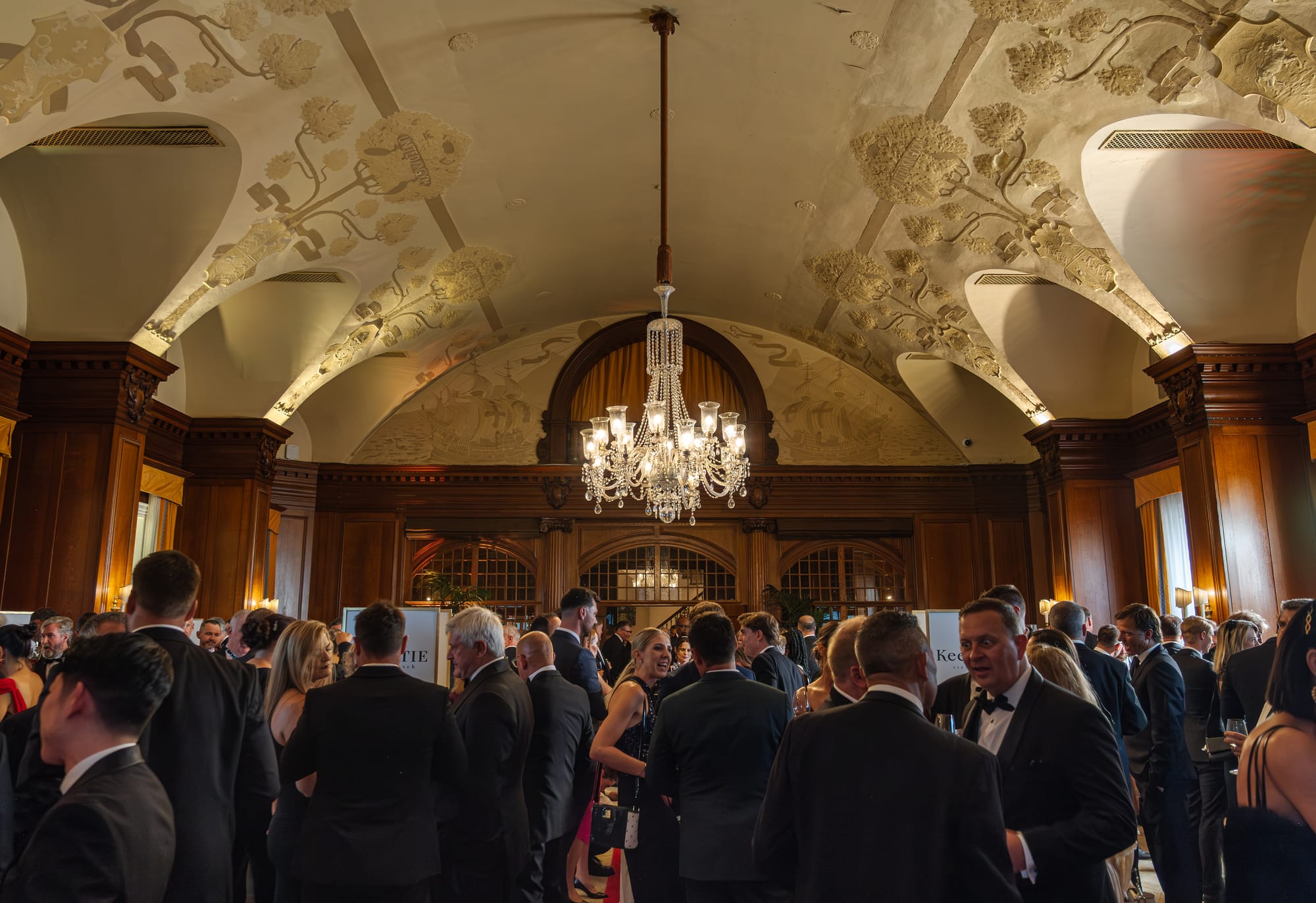Guests mingling beneath the chandelier at the reception