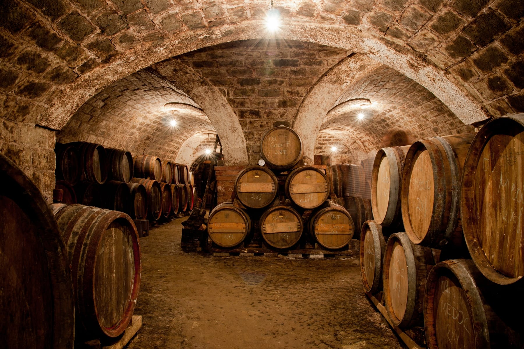 Oak barrels resting in a candlelit wine cellar